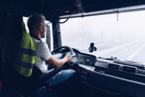 Handsome driver at the wheel of a truck at work.