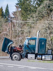 Broken big rig semi truck with an open hood and loaded semi trai