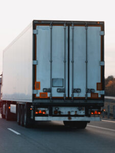 Modern white semi-trailer trucks on the highway driving in the right lane. Commercial vehicle for shipping and post delivery. Shipping of the goods on land with a door-to-door delivery process.